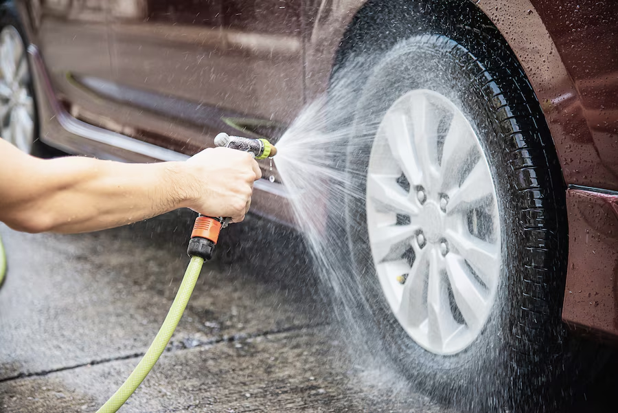 pessoa lavando o pneu de carro usando uma lavadora de alta pressão